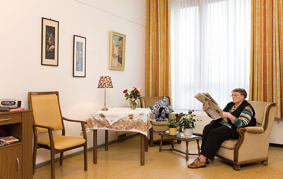 Eine Bewohnerin sitzt in ihrem Zimmer und liest 