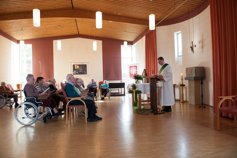 Ein Diakon rechts liest eine Messe vor Gläubigen in der Hauskappelle (Udo Keus)