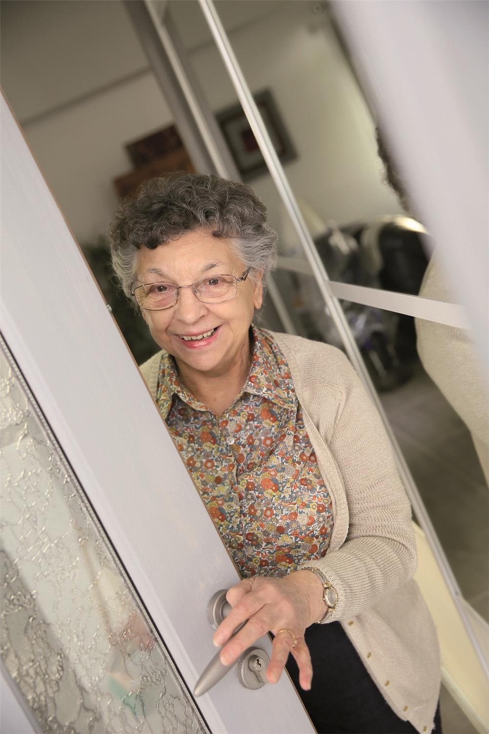 Ältere Frau die eine Tür öffnet (© „goodluz" / Fotolia.com)