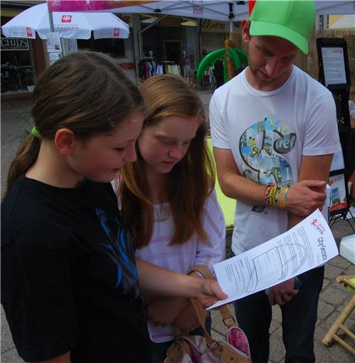 Jugendliche nehmen am City-Geocache teil und lesen sich die erste Aufgabe durch. 