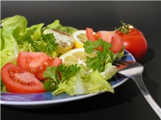 Ein Teller mit grünem Salat und Tomaten und einer Gabel / Fotolia