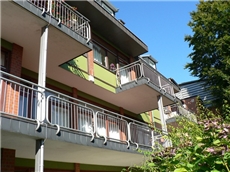 Fassade des Hauses mit Balkons im Grünen / Astrid Heyer