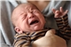 Süßes kleines Neugeborenes ist hungrig und verärgert und weint stark und lädt seine Eltern ein, es zu füttern und ihr Problem zu lösen. / guruXOOX/iStock.com