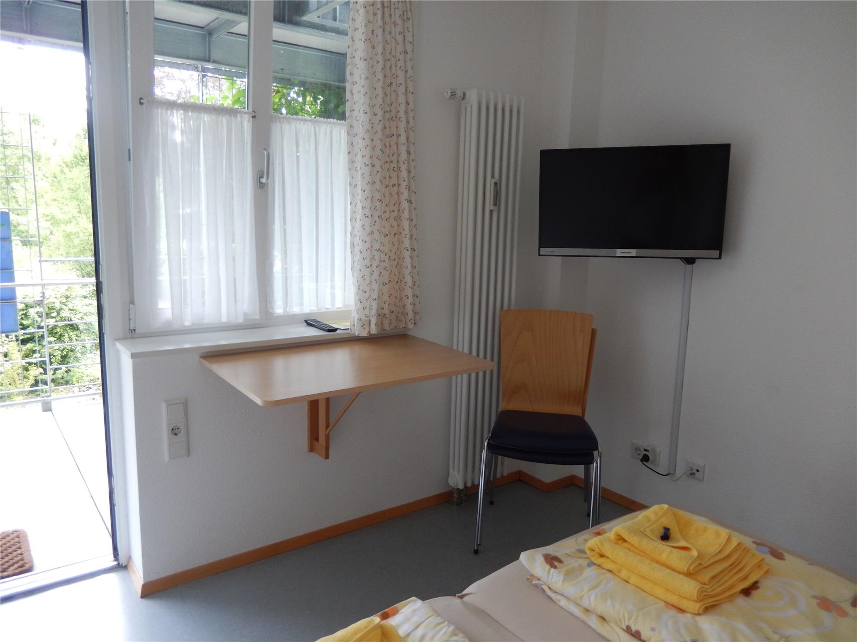 Gästezimmer - Blick vom Bett, Fernseher, Fenster und Tisch (Caritas Konstanz)