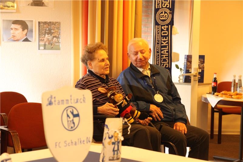 Hinter Schalke-Devotionalien sitzt ein älteres Ehepaar 