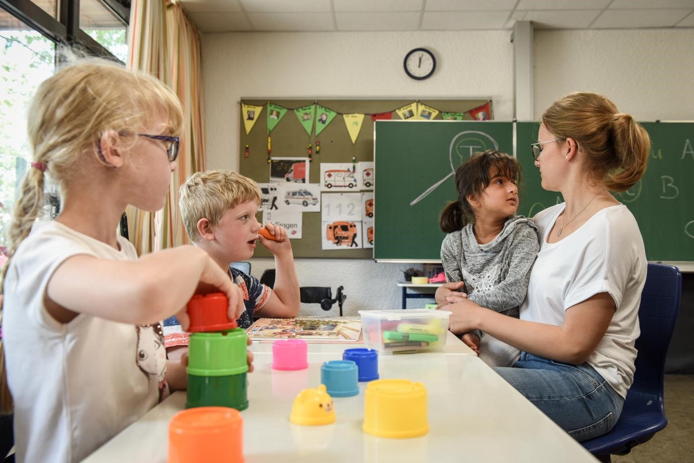Eine Freiwillige mit drei Kindern mit geistiger Behinderung am Tisch (Deutscher Caritasverband/Julia Steinbrecht, KNA)