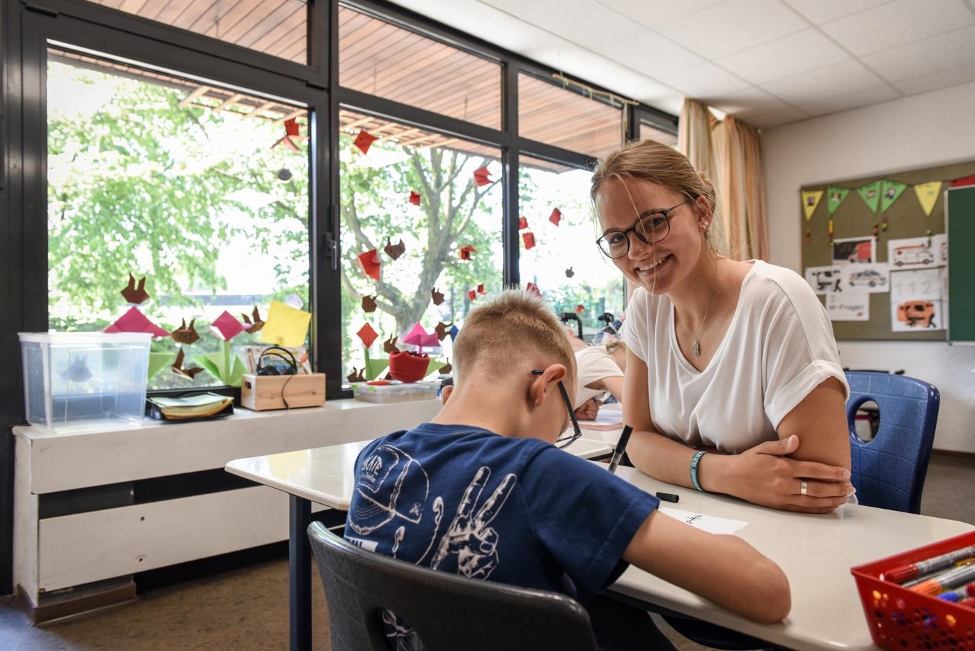 Eine jungen Freiwillige mit einem Jungen am Schreibtisch (Deutscher Caritasverband/Julia Steinbrecht, KNA)
