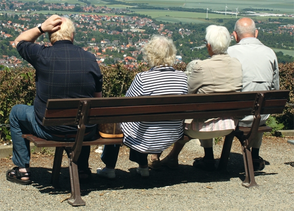 Vier alte Menschen sitzen auf einer Bank und blicken in eine tiefergelegene Landschaft (Osterland/Fotolia)