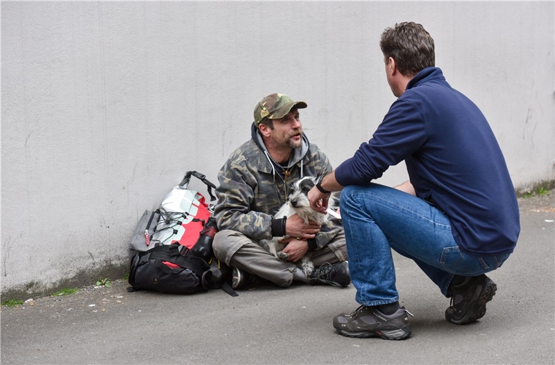 Sozialarbeiter und Obdachloser unterhalten sich auf der Straße