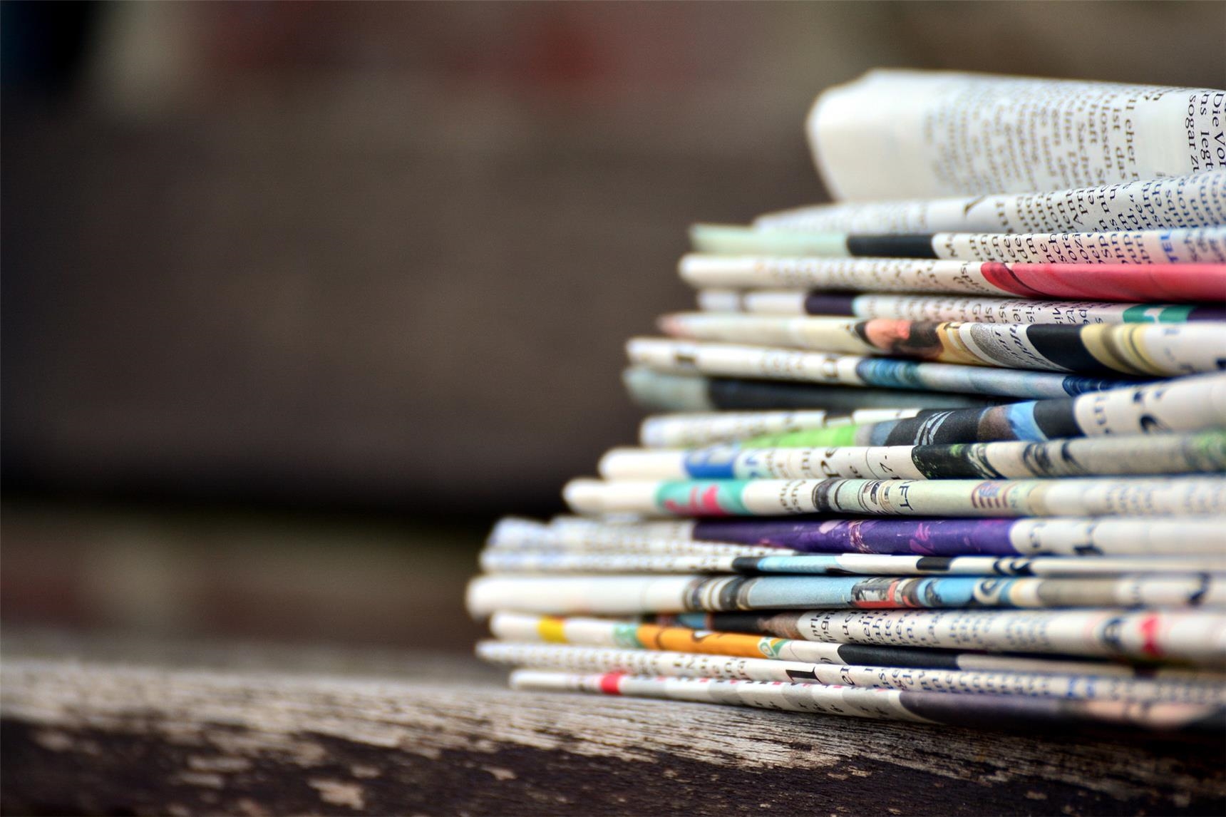 Ein Stapel Zeitungen vor dunklem Hintergrund