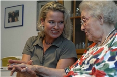 Eine ehrenamtliche Mitarbeiterin besucht eine ältere Bewohnerin eines Altenzentrums und hält ihre Hand.  / Martin Oppitz/KNA/Carinet
