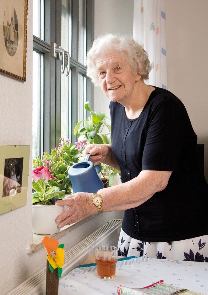 Eine Bewohnerin gießt ihre Zimmerblumen 
