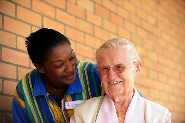 Lächelnde Pflegerin und fröhliche ältere Dame