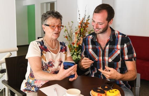 junger Mann zeigt älterer Frau den Umgang mit dem Handy (Deutscher Caritasverband/Harald Oppitz, KNA)