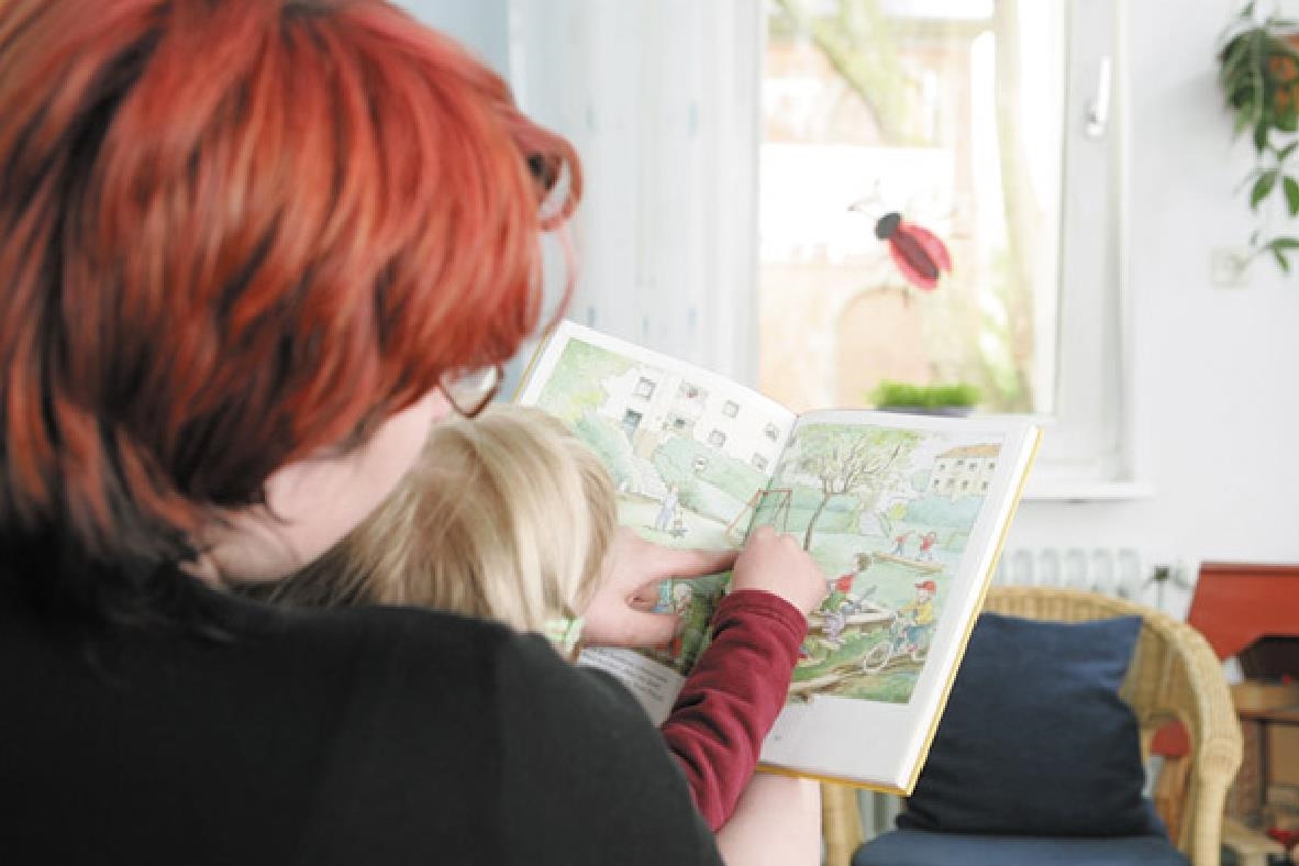 Frau liest Kind etwas vor; Ansicht von hinten 
