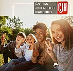 4 Jugendliche sitzen auf einer Wiese und schaun uns im Sonnenschein an.