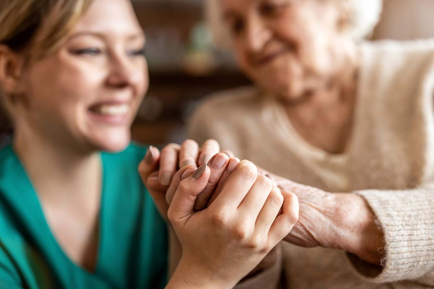 Eine junge Frau hält die Hand einer alten Frau.