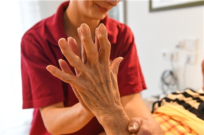 Pflegerin und ältere Dame legen liebevoll ihre Hände übereinander