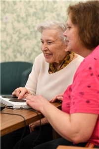 Pflegerin mit Seniorin am Computer