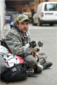obdachloser Mann mit seinem Hund auf dem Schoß