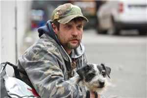  obdachloser Mann mit seinem Hund schaut gespannt auf die Straße