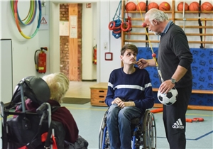 Zwei Menschen mit Behinderung und ein Betreuer in der Sporthalle