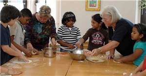 zwei Ehrenamtliche kochen mit zwei Kindern mit Migrationshintergrund