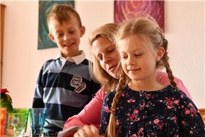 Familie Teil 5 - 004 Mutter, Tochter und Sohn betrachten gemeinsam etwas auf dem Tisch