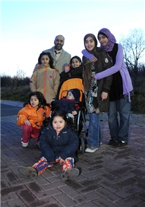 Eine achtköpfige Familie mit Migrationshintergrund schaut in die Kamera