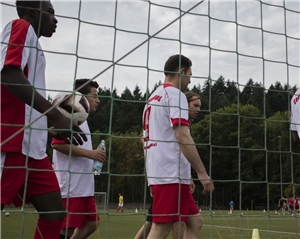 Mehrere Flüchtlinge gehen in Fußballtrikots zum Kicken