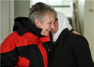 Frau mit Kopftuch küsst Caritas-Mitarbeiterin auf die Backe