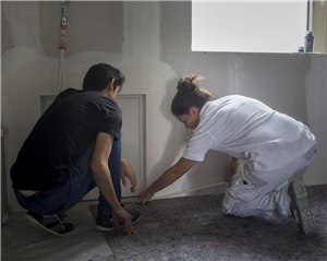 Malerin und Flüchtling arbeiten gemeinsam in einer Wohnung