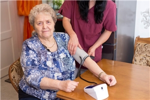 Pflegerin misst einer älteren Dame den Blutdruck 