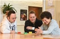 Gemeinsam spielen Frau und Mann spielen zusammen mit Betreuerin ein Brettspiel.