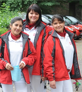 Drei Mitarbeiterinnen einer Caritas-Sozialstation vor den Dienstfahrzeugen