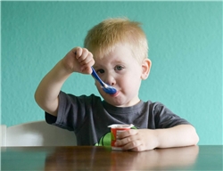 Ein Junge isst Pudding aus einem Becher.