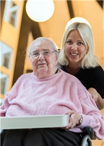 Eine ältere, pflegebedürftige Dame im Gespräch mit einer Pflegefachkraft.
