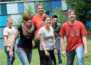 Gruppe Freiwilliger Gruppe Freiwilliger spielt Fangen auf dem Rasen