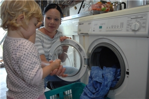 junge Mutter mit Kleinkind am Wäsche waschen