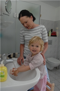 Frau mit Kleinkind am Hände waschen