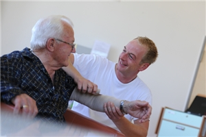 Ein Pfleger verbindet einem älteren Mann den Arm.