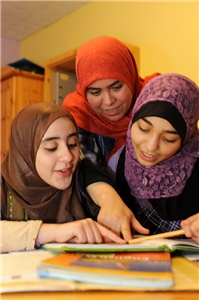 Frauen mit Migrationshintergrund schauen gemeinsam ein Buch an