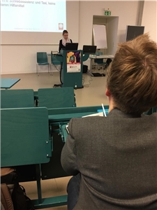 Junge Frau hält in einem Hörsaal der Technischen Hochschule in Köln eine Powerpoint-Präsentation. Sie steht an einem Stehpult, im Vordergrund sieht man eine Zuhörerin.