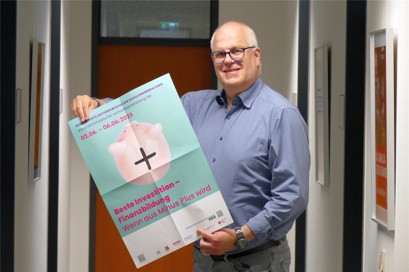 Eine Person hält ein hochformatiges Plakat in der Hand. Es zeigt ein Sparschwein und bringt die Forderung nach mehr finanzieller Bildung zum Ausdruck. 