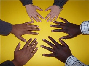 Hände verschiedener Hautfarben ausgestreckt vor gelbem Hintergrund