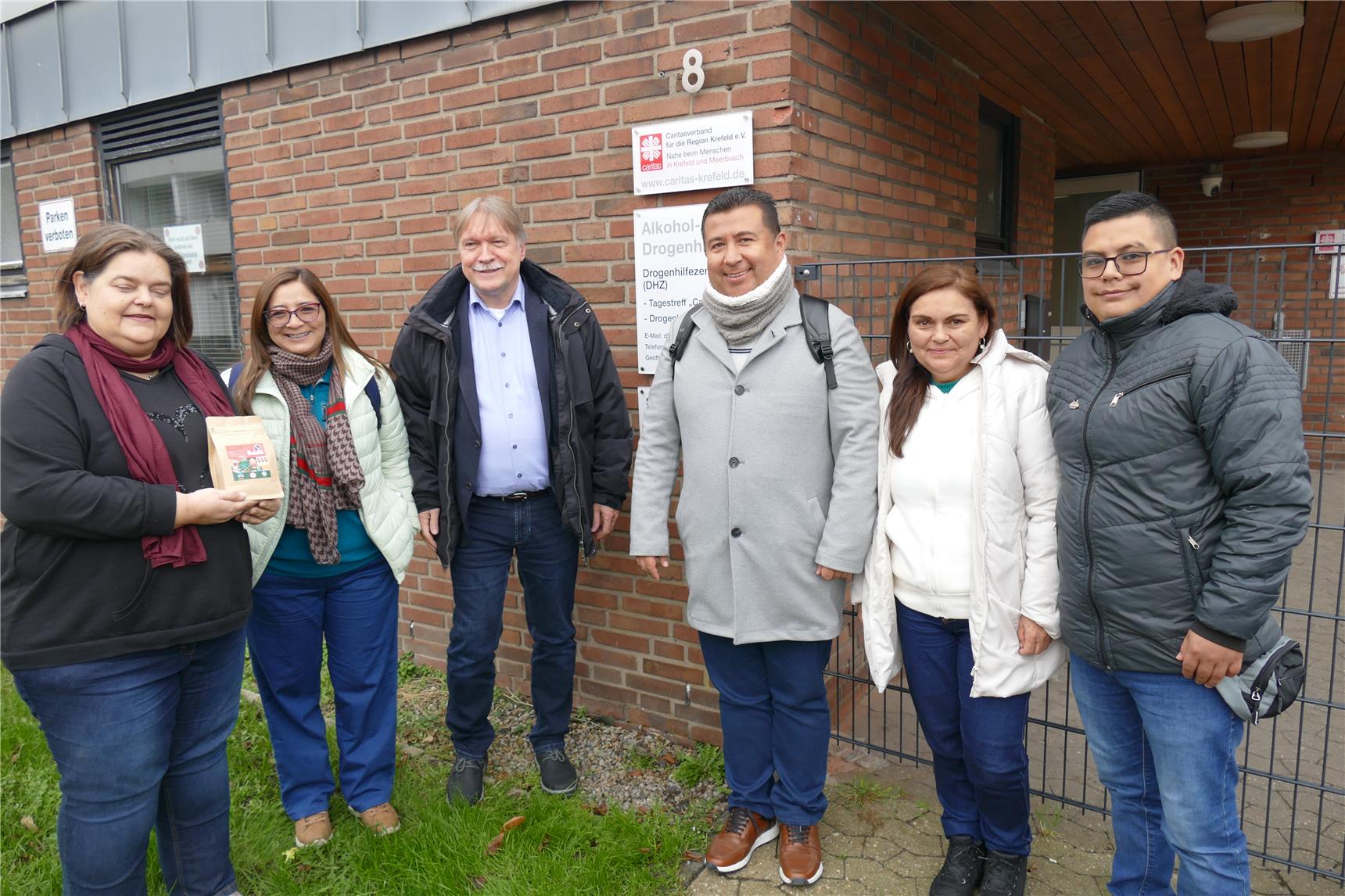 Sechs Personen stehen im Halbkreis vor dem Drogenhilfezentrum der Caritas in Krefeld.