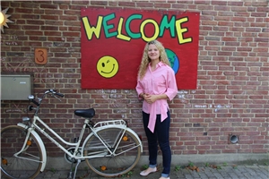 Frau vor auf eine Wand gmaltem Schriftzug 'Welcome'