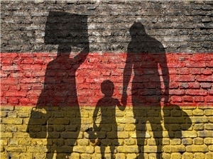 Silhouette einer Flüchtlingsfamilie vor Deutschland-Fahne