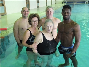 Fünf Menschen stehen zusammen im Schwimmerbecken des Hallenbades