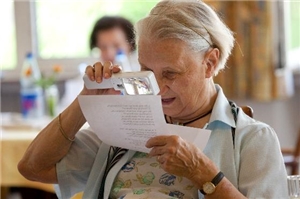 Eine Frau liest mit einer Lupe genau einen Text